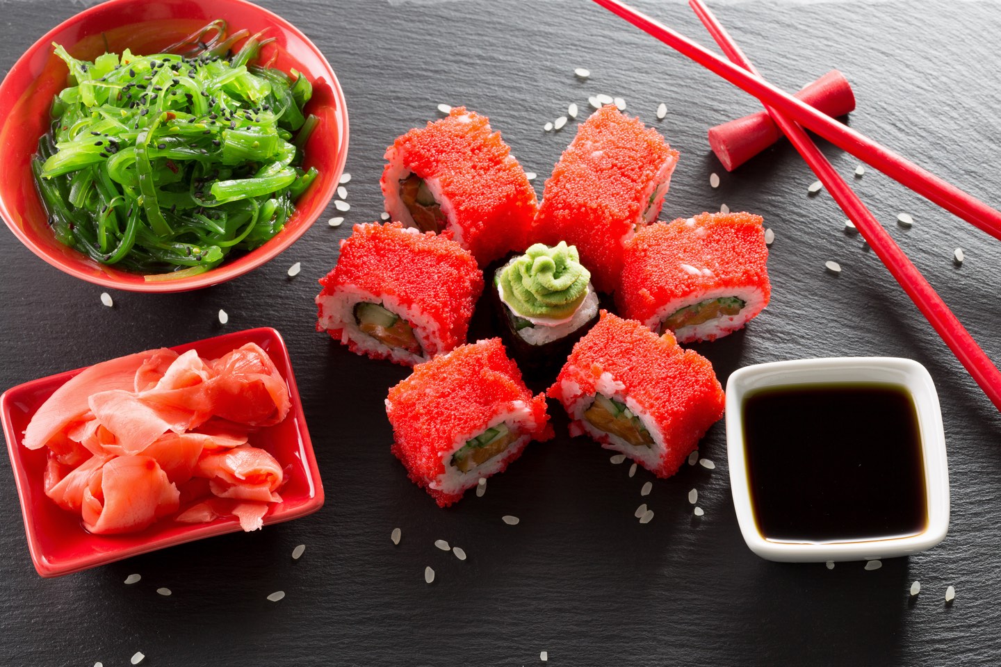 sushi and rolls with green sea salad on a slate table